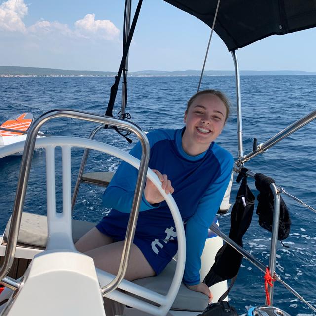 Tochter am Steuerrad einer Segelyacht vor Kroatien